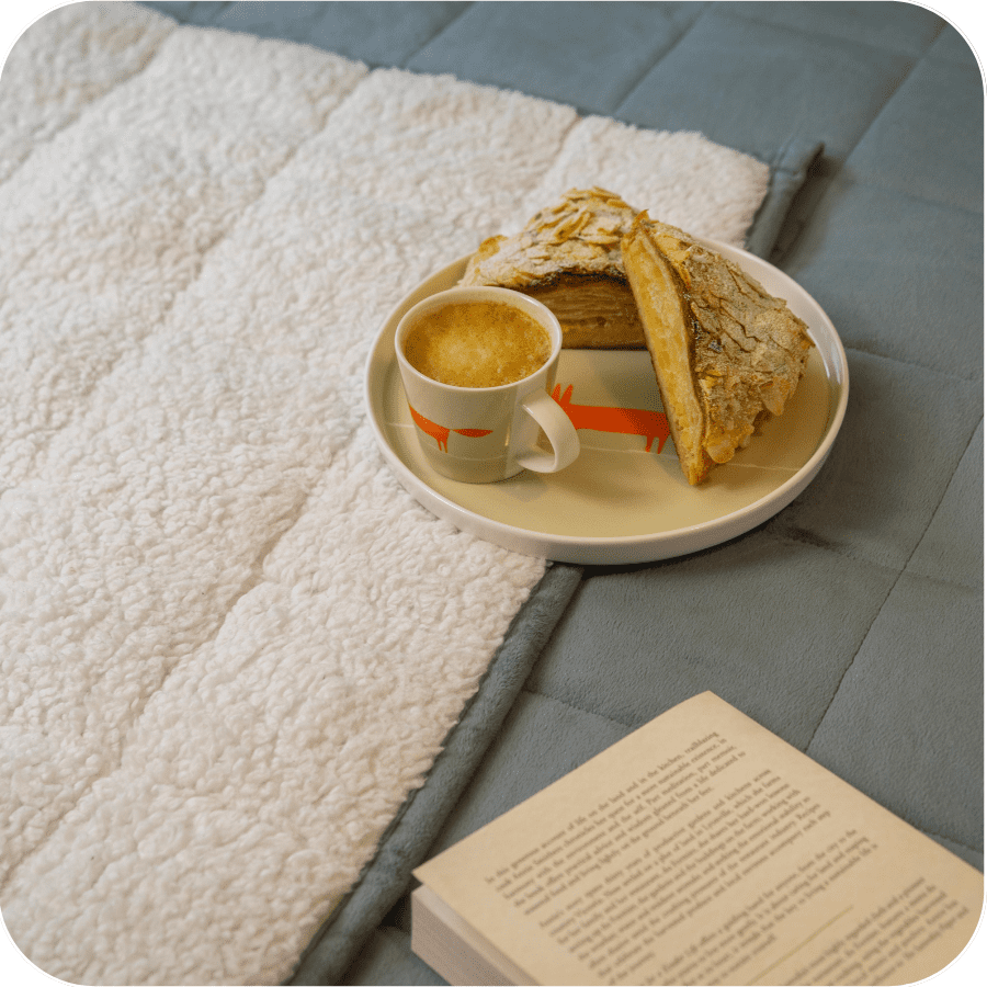 Pastry and coffee on plate on weighted blanket